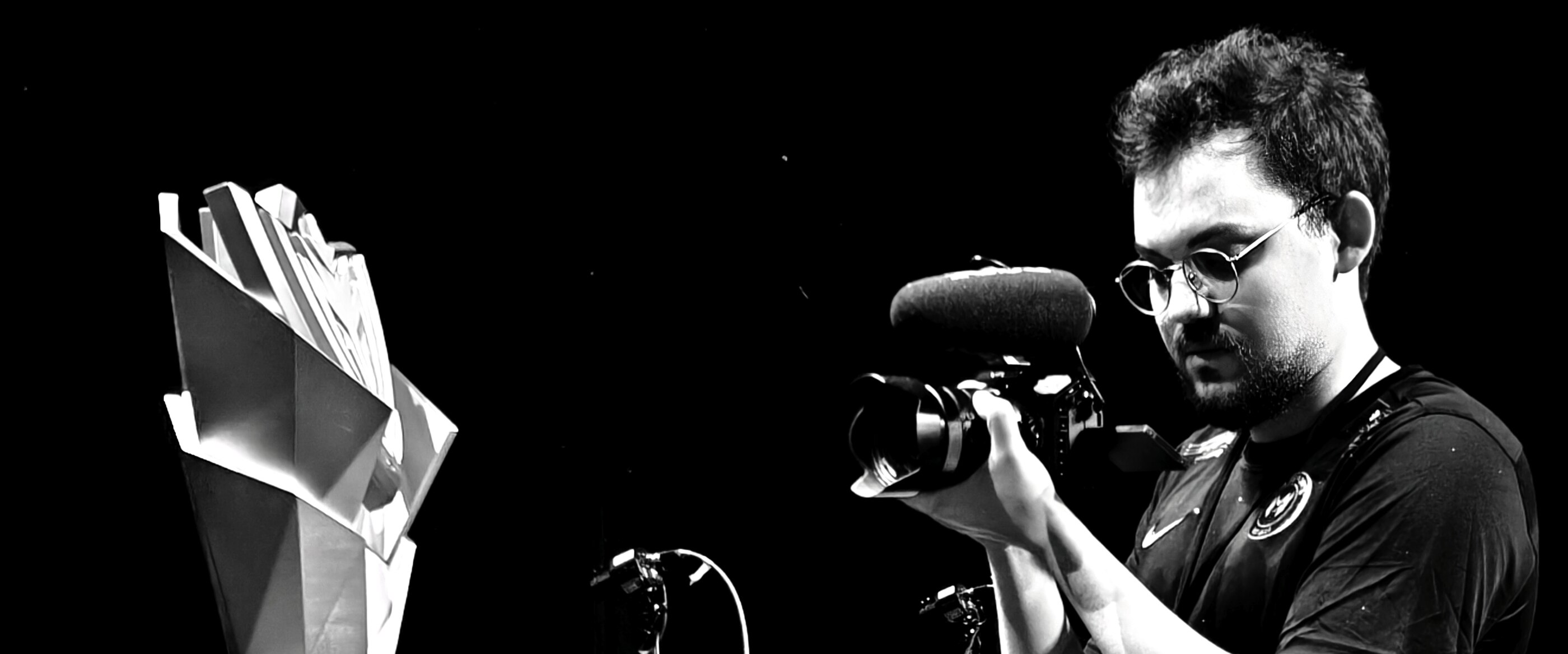 Ahmed Yıldız operating his cinema camera, a championship trophy in the foreground, in black and white