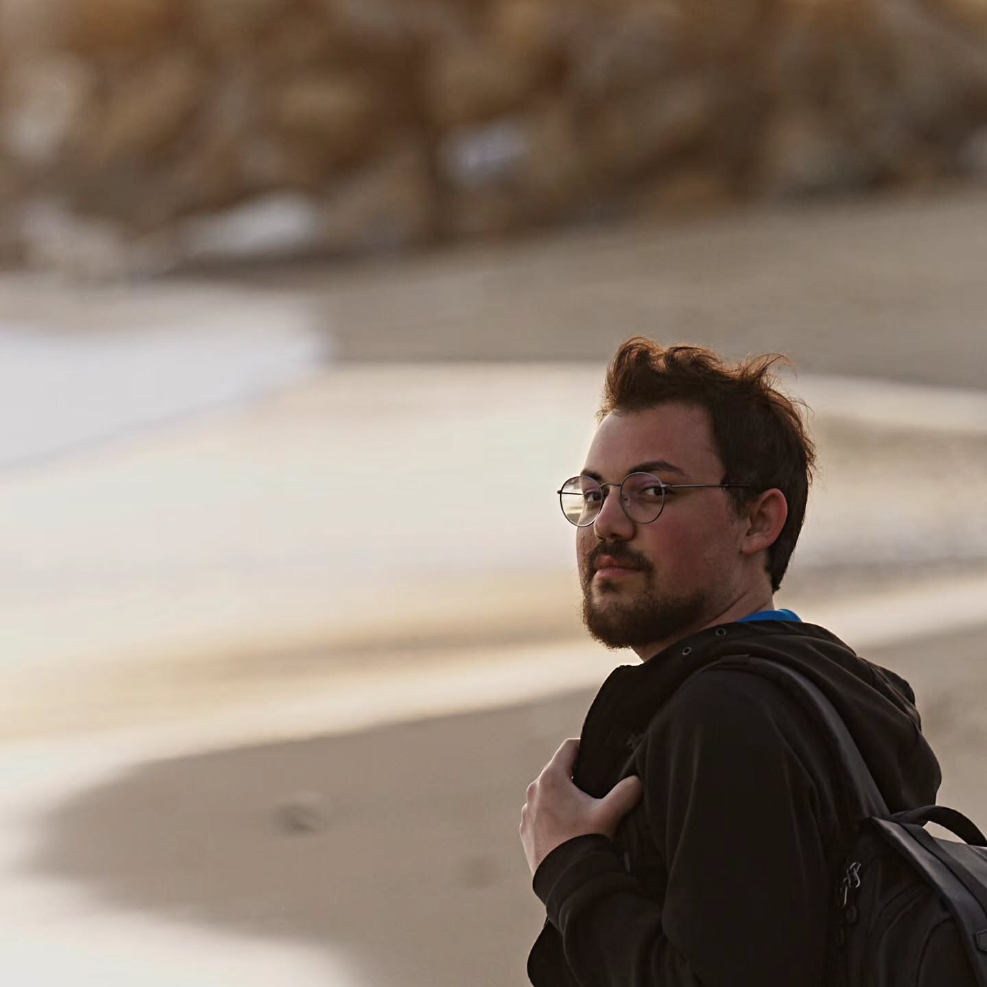 Ahmed Yıldız glancing back over his shoulder on the coast in warm light