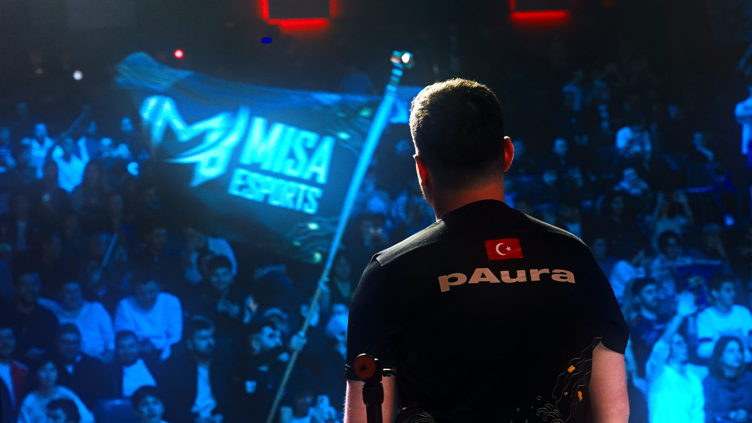 Player pAura from behind facing a fully lit arena crowd in blue light
